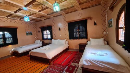 a room with two beds and two windows at kasbah amlal in Tinerhir
