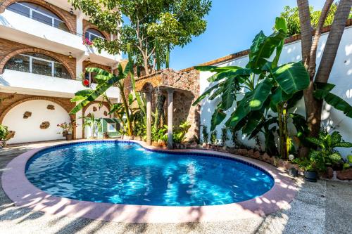 a swimming pool in front of a house with trees at Charming Colonial Mexican Hacienda in Puerto Vallarta