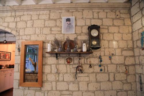 a stone wall with a clock and a mirror at Alaçatı Kavalalı Otel in Alaçatı
