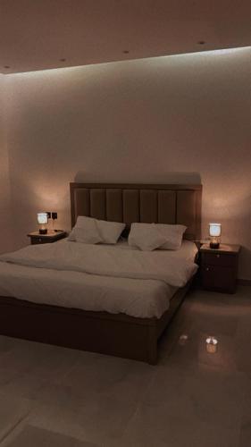 1 dormitorio con 1 cama grande y 2 lámparas en las mesas en غرفه وصاله انيقه بالعقيق, en Riad