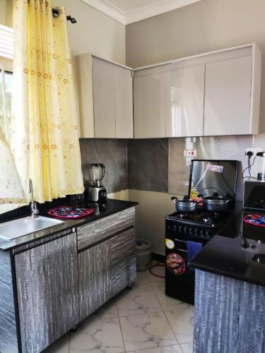 a kitchen with white cabinets and a stove top oven at VaanaKabod in Kampala