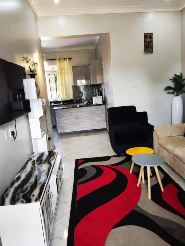 a living room with a couch and a red and black rug at VaanaKabod in Kampala
