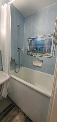 a blue tiled bathroom with a tub and a sink at Apartment with garden near metro! in Stockholm