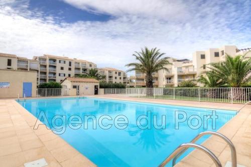 - une piscine bordée de palmiers et de bâtiments dans l'établissement T2 résidence piscine et direct plage, à Saint-Cyprien