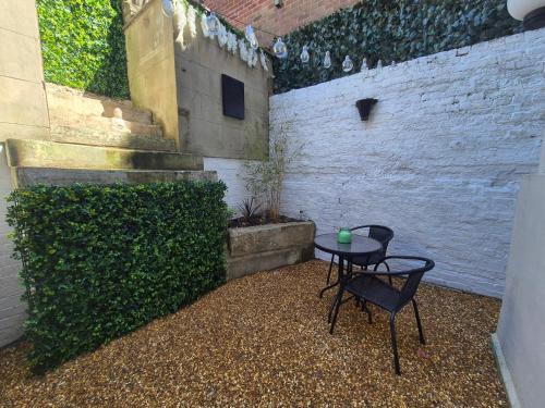 a patio with a table and a green hedge at Dog-Friendly Basement Apartment with Garden - Southsea, Portsmouth #26a in Portsmouth