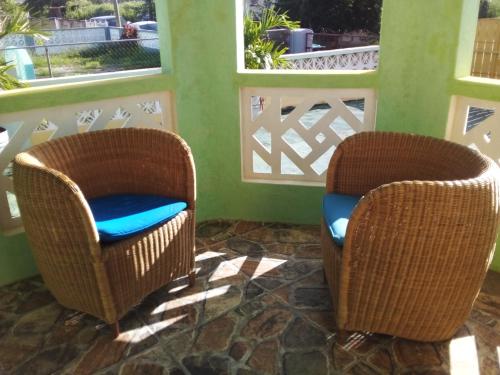 two wicker chairs sitting in a room with windows at Palm View Room 1 in Christ Church