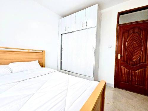 - une chambre avec un lit blanc et une porte en bois dans l'établissement Nyahururu 1 BR Apartment, à Nyahururu