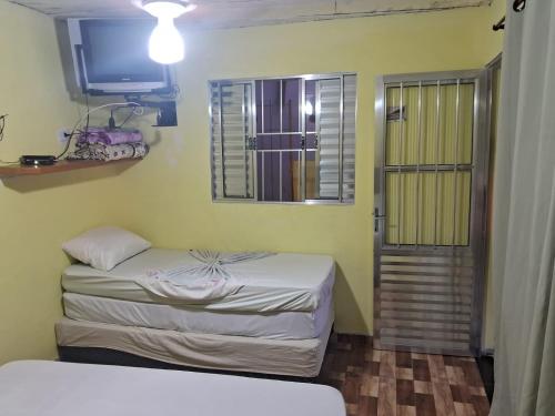 - une petite chambre avec 2 lits et une fenêtre dans l'établissement Casa da teka, à Pedro de Toledo