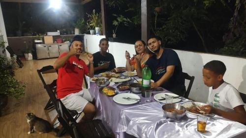 un grupo de hombres sentados alrededor de una mesa comiendo comida en Repouso do corcovado hostel, en Río de Janeiro