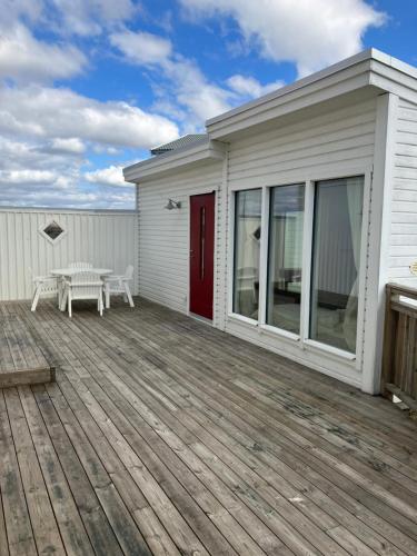 une maison blanche avec une terrasse et une table dans l'établissement Eget gästhus i västkustpärlan Skärhamn, à Skärhamn