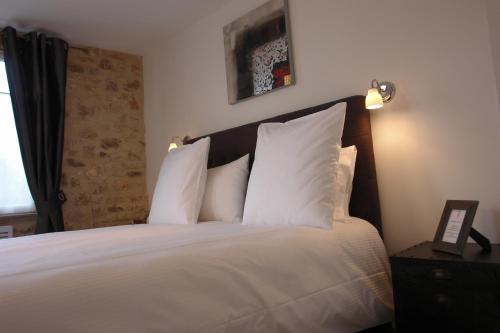 a bedroom with a large bed with white pillows at Hotel L'Aunette Cottage in Chamant