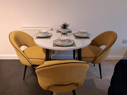 einen Tisch mit Stühlen, Teller und Schüsseln darauf in der Unterkunft Stunning Station Apartment in Kent