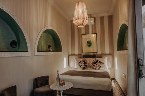 a bedroom with a bed and a table and a chandelier at Riad Bab Ahmar in Marrakesh