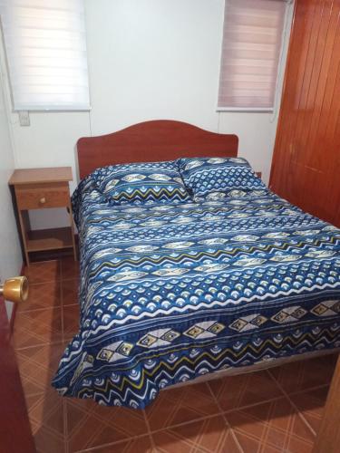 a bed with a blue and white comforter in a room at Hospedaje Martita Patagonia in Coihaique