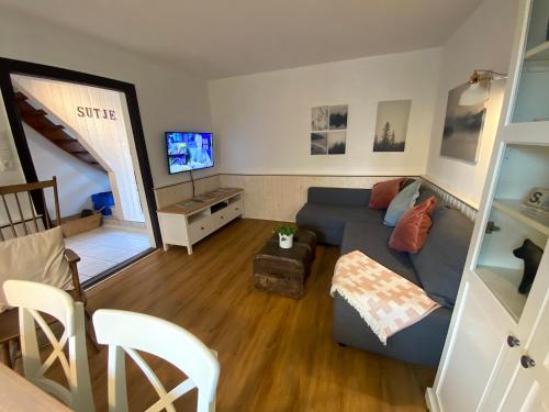 a living room with a blue couch and a tv at Ferienhaus Sutje in Loose