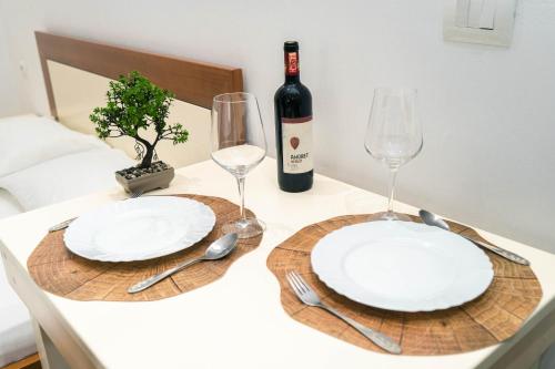 a table with two white plates and a bottle of wine at Vila Anxhelo in Vlorë