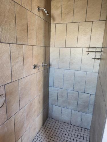 uma casa de banho com um chuveiro, pisos em azulejo e um chuveiro. em Le Petit em Vredendal