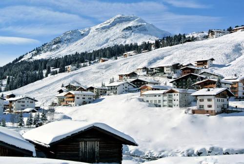 a village covered in snow with a mountain in the background at Chalet Schneekristall in Lech am Arlberg