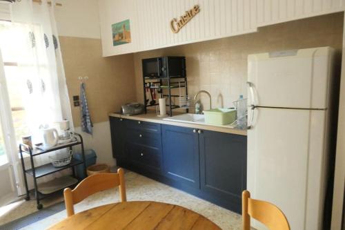 Il comprend une cuisine équipée d'un réfrigérateur blanc et d'une table en bois. dans l'établissement Beau T3, calme, parking gratuit, à Pollestres