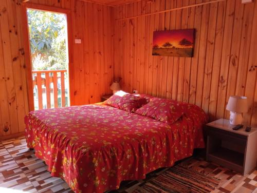 1 dormitorio con 1 cama con manta roja en "PINARES DEL MAR" Pequeñas cabañas ECO rusticas sello "S", en Isla Negra