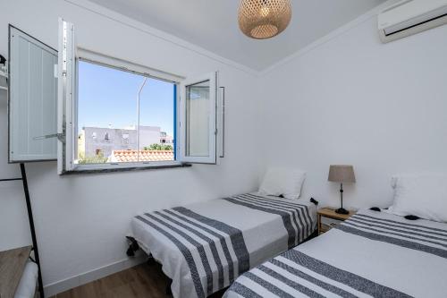 Duas camas num pequeno quarto com uma janela em Casa Flores - T2 Santa Luzia - Tavira em Santa Luzia