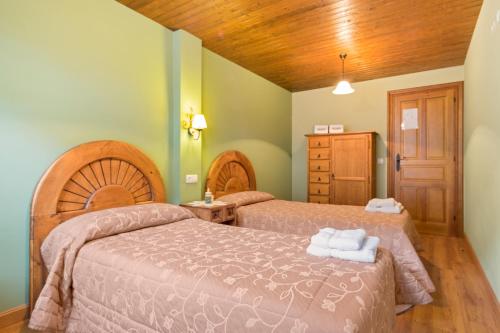 ein Schlafzimmer mit zwei Betten und einer Holzdecke in der Unterkunft Apartamentos Blanca Senda del Oso in Páramo