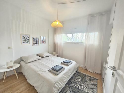 Un dormitorio blanco con una cama grande y una mesa en Maison proche toutes commodités, en Le Bouscat