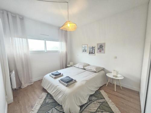 ein weißes Schlafzimmer mit einem Bett und einem Tisch in der Unterkunft Maison proche toutes commodités in Le Bouscat