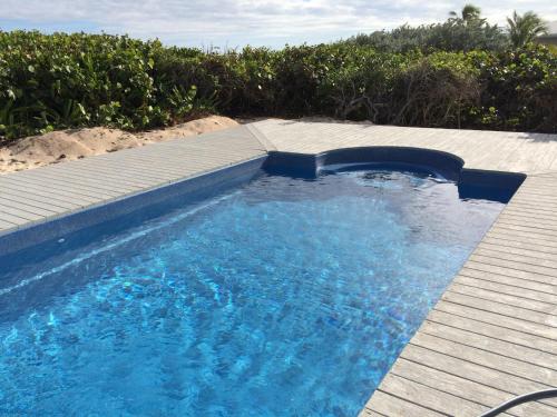 a swimming pool with a wooden deck and blue water at Southern Cross of the Abacos in Hope Town