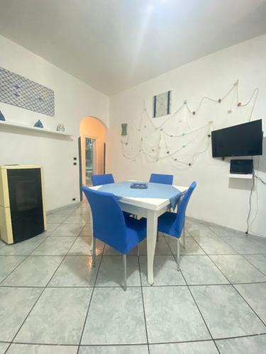 une salle à manger avec une table blanche et des chaises bleues dans l'établissement Tiffany Holiday Home, à Ischia