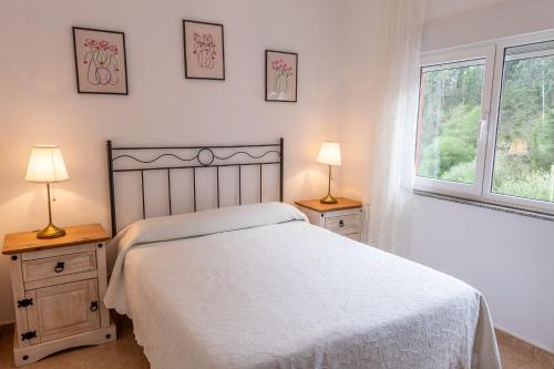 1 dormitorio con 1 cama blanca y 2 mesitas de noche en Apartamentos Ondina, en Soto de Luiña