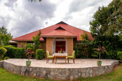 a table and chairs in front of a house at Sharp Island Gorilla Lodge, Lake Bunyonyi in Kashasha