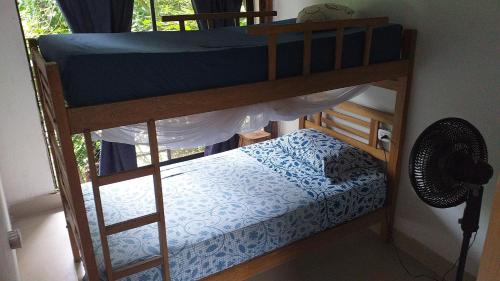 a bunk bed in a room with a fan at Sierra Tayrona hostel in El Zaino