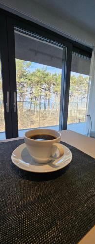 a cup of coffee on a plate on a table at Pine & Sun Apartment - Hevenia Pogorzelica in Pogorzelica