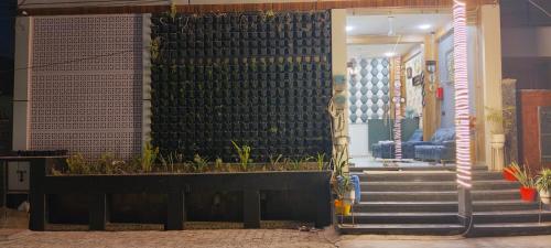 a lobby with stairs and a black wall with plants at Hotel Olive Smart Stay in Agra