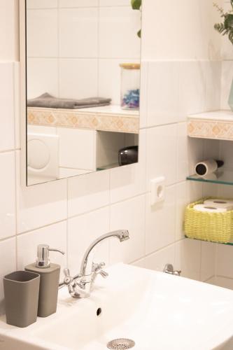 Baño blanco con lavabo y espejo en Gemütliche Wohnung mit kleiner Terrasse - Nah am Stadion Frankfurt und Flughafen en Mörfelden-Walldorf