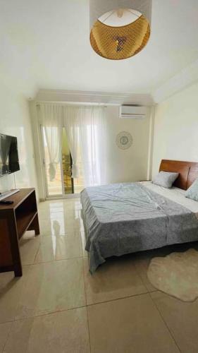 een slaapkamer met een bed, een bureau en een televisie bij F3 Chic et Cosy très accessible in Dakar