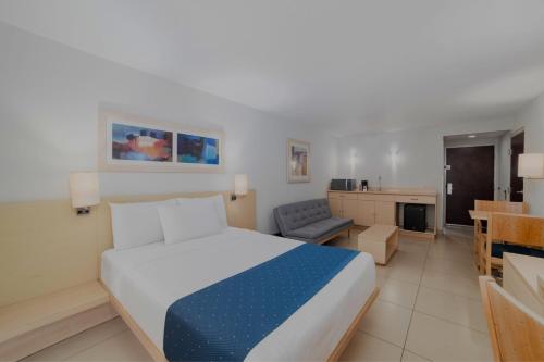 a bedroom with a bed and a couch and a table at City Express by Marriott Minatitlán in Minatitlán