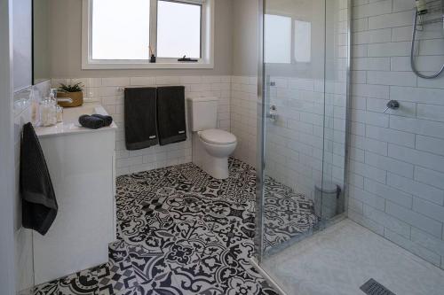 a bathroom with a toilet and a glass shower at Kalang BnB St Helens in St Helens