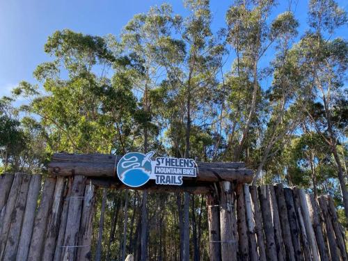 a sign on a wooden fence with trees in the background at Kalang BnB St Helens in St Helens