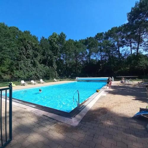 une grande piscine bleue avec des personnes assises autour de celle-ci dans l'établissement La Villa Varanguaise 3 étoiles Lacanau, à Lacanau