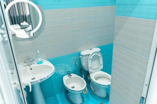 a blue bathroom with a toilet and a sink at Vila Anxhelo in Vlorë