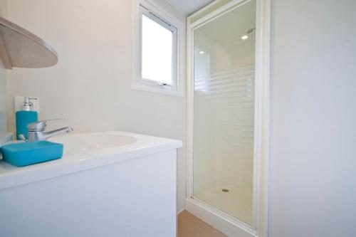 une salle de bain blanche avec un lavabo et une douche dans l'établissement Chalet les chênes verts - Périgord proche grottes de Lascaux, à Saint-Amand-de-Coly