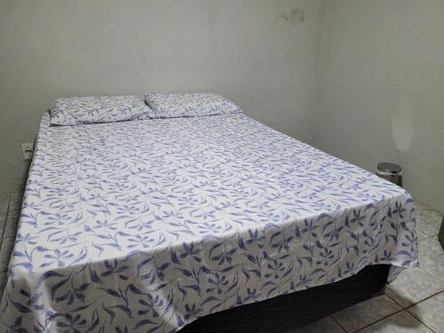a bed with a blue and white comforter on it at Quarto - Canto Juazeirense in Juazeiro do Norte
