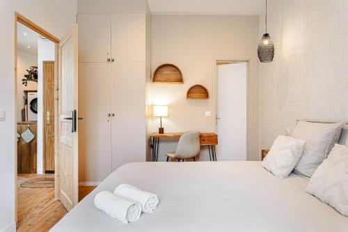 Un dormitorio con una gran cama blanca y un escritorio. en Cosy appart proche du marché, en La Rochelle