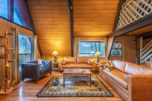 a living room with leather couches and a table at Gatlinburg Cabin With Breathtaking Views, Hot Tub, Sauna, 10 min to downtown and National Park in Gatlinburg