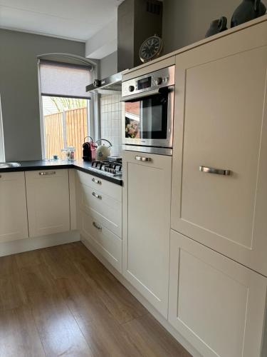 a kitchen with white cabinets and a stove top oven at Vakantiehuis Klaartje Kip Enschede tot 4 personen, landelijk gelegen! in Enschede