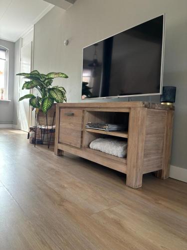 a wooden entertainment center with a large flat screen tv at Vakantiehuis Klaartje Kip Enschede tot 4 personen, landelijk gelegen! in Enschede