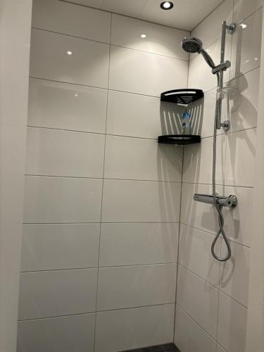 a white tiled bathroom with a shower with at Vakantiehuis Klaartje Kip Enschede tot 4 personen, landelijk gelegen! in Enschede