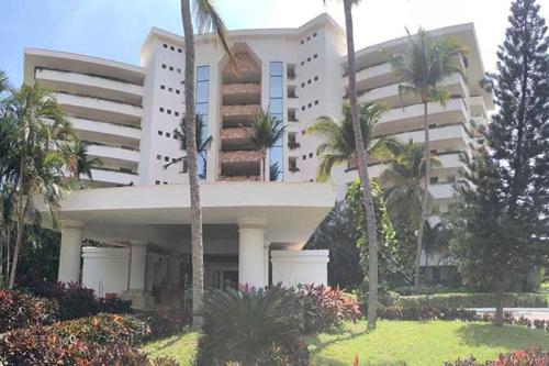 a large building with palm trees in front of it at Increíble depto. en playa privada. in Acapulco